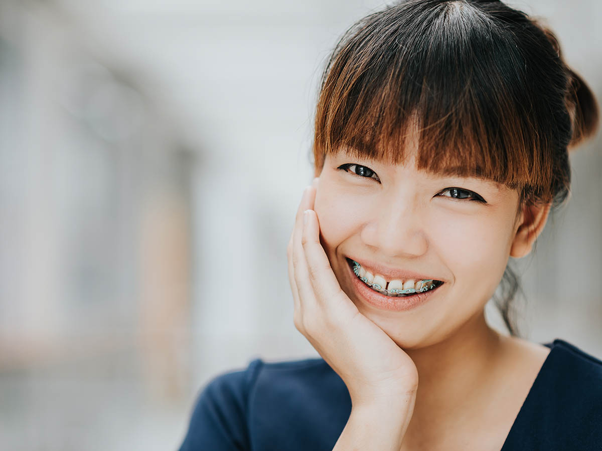 Portrait of happy young pretty Asian girl with braces smiling.